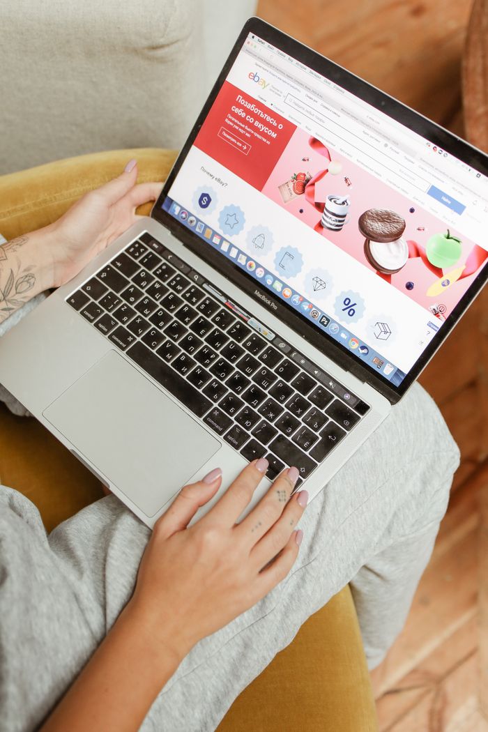 Services A woman sits comfortably indoors, browsing an online shopping website on her laptop.
